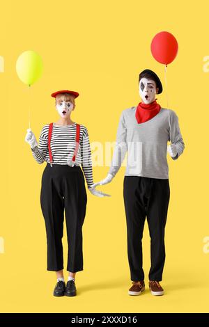 Ein paar Pantomimisten mit Ballons auf gelbem Hintergrund Stockfoto