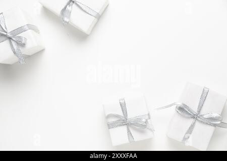 Vier weiße Geschenkboxen mit silbernen Bändern auf weißem Hintergrund mit Kopierraum. Stockfoto