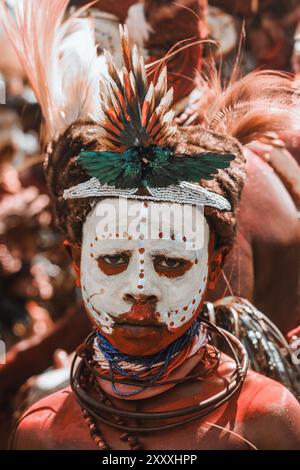 Ein junger Junge aus der Provinz Hela, Papua-Neuguinea, blickt direkt in die Kamera und zeigt seine lebhafte traditionelle Kleidung mit Stolz und Selbstvertrauen. Stockfoto