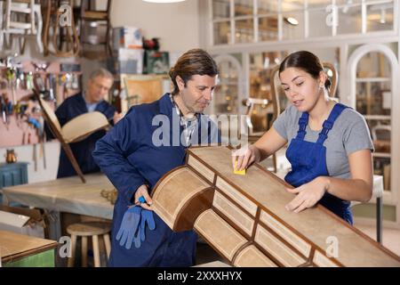 Männliche und weibliche Möbelmacher arbeiten an Vintage-Kommode in der Werkstatt Stockfoto