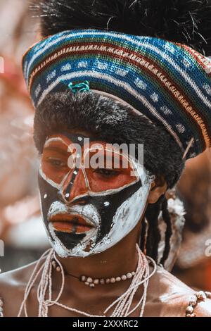 Eine Frau aus dem Hochland in Papua-Neuguinea, die in lebendigen traditionellen Gewändern gehalten ist und die reichen Farben und das kulturelle Erbe ihrer Region zeigt. Stockfoto