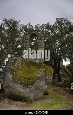 Alte Ruine Steingebäude bedeckt mit Moos in der Nähe der Kapelle Sao Pedro mit Bäumen und Felsblöcken in Monsanto, Portugal, Europa Stockfoto