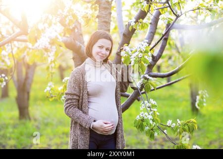 Glücklich schöne schwangere Frau im blühenden Garten Stockfoto