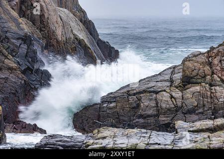 Wellen stürzen während eines Wintersturms gegen Klippen Stockfoto