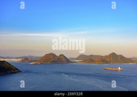 Frachtschiff am Eingang der Bucht von Guanabara in Rio de Janeiro mit niteroi Stadt im Hintergrund anreisen Stockfoto