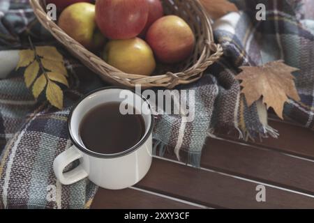 Heiße Tasse Tee karierte Decke Äpfel und Blätter im Herbst auf alten hölzernen Hintergrund Stockfoto