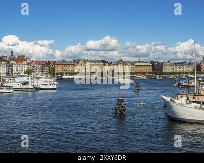 Blick auf die Stadt mit vielen bunten Gebäuden am Wasser und Booten, unter blauem Himmel, stockholm, ostsee, schweden, skandinavien Stockfoto