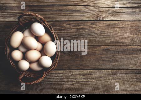 Flach legen mit Korb voller Bio-Hühnereier auf Holz Hintergrund. Bio-Haushaltskonzept mit Eiern von Freiland- und Weidegehennen Stockfoto