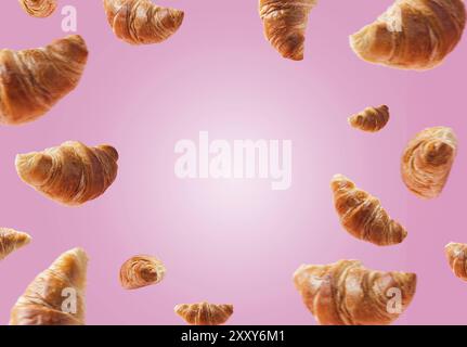 Viele frisch gebackene Croissants schweben oder fliegen. Croissants isoliert auf rosa Hintergrund. Levitation-Szene. Platz für Text kopieren. Werbung Stockfoto