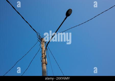 Foto des Strommasts unter klarem blauem Himmel am Morgen. Foto des Strommasts mit freistehendem Draht. Stromversorgungskabel Stockfoto