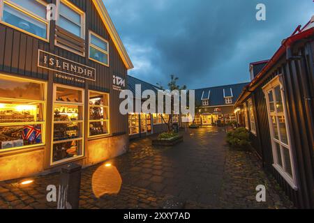 REYKJAVIK, ISLAND, 06. JULI: Kringlan Shopping Mall beleuchtet bei Nacht mit dem Islandia Souvenir Shop im Vordergrund in Reykjavik, Island auf Ju Stockfoto