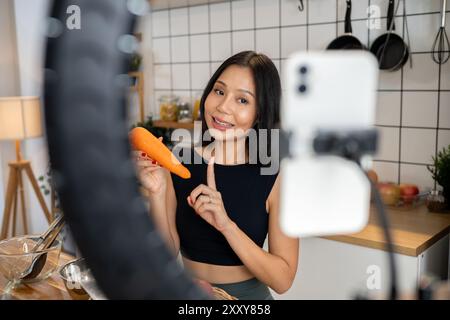 Eine attraktive asiatische Food-Bloggerin oder Content-Creatorin kocht vor der Kamera, spricht und zeigt ihre Zutaten für ein spezielles Menü Stockfoto