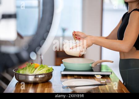 Ein zugeschnittenes Bild einer Food Bloggerin kocht vor der Kamera und nimmt ein Video auf, wie sie in ihrer Küche gesundes Essen zubereitet. Stockfoto