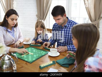 Glückliche junge Familie Plaing Brettspiel mit zwei Töchtern Stockfoto