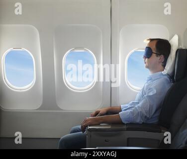 Porträt des Mannes entspannen in Sleaping Maske im Flugzeug Stockfoto