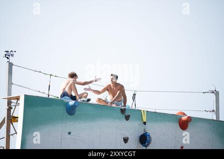 Brooklyn, Usa. August 2024. Beim North Face Climb Festival am Pier 5 des Brooklyn Bridge Parks in New York City schütteln sich die Teilnehmer die Hände. Die North Face Company veranstaltete ein Climb Festival im Brooklyn Bridge Park Credit: SOPA Images Limited/Alamy Live News Stockfoto