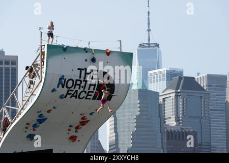 Brooklyn, Usa. August 2024. Beim North Face Climb Festival am Pier 5 im Brooklyn Bridge Park in New York City springt ein Kletterer ins Wasser. Die North Face Company veranstaltete ein Climb Festival im Brooklyn Bridge Park Credit: SOPA Images Limited/Alamy Live News Stockfoto