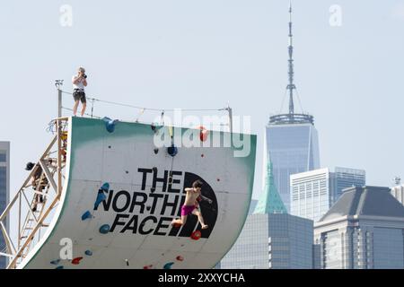 Brooklyn, Usa. August 2024. Beim North Face Climb Festival am Pier 5 im Brooklyn Bridge Park in New York City springt ein Kletterer ins Wasser. Die North Face Company veranstaltete ein Climb Festival im Brooklyn Bridge Park Credit: SOPA Images Limited/Alamy Live News Stockfoto