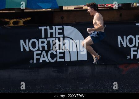 Brooklyn, Usa. August 2024. Beim North Face Climb Festival am Pier 5 im Brooklyn Bridge Park in New York City springt ein Kletterer ins Wasser. Die North Face Company veranstaltete ein Climb Festival im Brooklyn Bridge Park (Foto: Derek French/SOPA Images/SIPA USA) Credit: SIPA USA/Alamy Live News Stockfoto