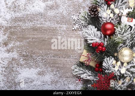 Weihnachtsdekoration mit festlichen Ornamenten auf rustikalem hölzernem Hintergrund und Schnee, rote Kugeln, Geschenkboxen mit Kopierraum, Vintage-Ton von oben Stockfoto