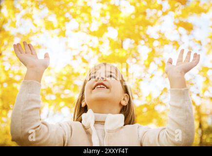 Porträt von ein glückliches kleines Mädchen spielen mit Herbst Blätter im Wald Stockfoto