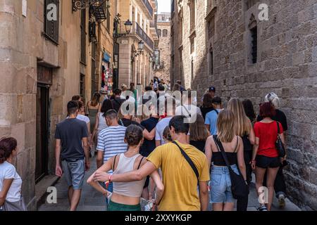 Eine große Gruppe von Touristen wird gesehen, wie sie entlang einer engen Straße zum nächsten Punkt von touristischem Interesse laufen, wo sie kurze Erklärungen vom Reiseleiter erhalten. Nach Angaben des World Travel and Tourism Council (WTTC) wird die Wirtschaftstätigkeit, die sich aus dem Tourismus in Spanien ergibt, in den nächsten zehn Jahren weiter zunehmen. Die Probleme der Massentourismus-Wirtschaft: Überfüllung der öffentlichen Räume, Müll, Lärm, mangelnde Nachhaltigkeit, Zoll, das Verschwinden traditioneller Läden ist bereits in Barcelona bemerkbar, wo einige Arbeiterviertel nach einem Rückgang der Zahl der Läden verlangen Stockfoto