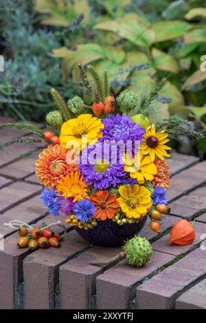 Spätsommerblumenanordnung von Sommerastern, Dahlien, Zinnien, Nelken, Hagebutten und Gräsern im Garten Stockfoto