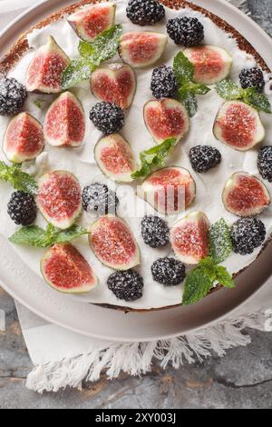 Hausgemachte Torte mit Feigen, Brombeeren und Frischkäse in Nahaufnahme auf einem Teller auf dem Tisch. Vertikale Draufsicht von oben Stockfoto