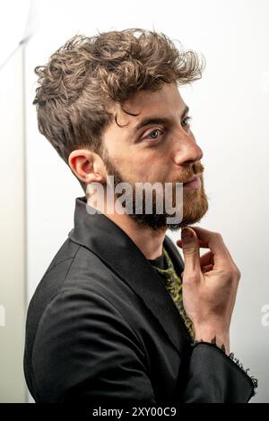 Nahprofil eines modischen jungen Mannes mit lockigem Haar und gepflegtem Bart. Sie demonstrieren den modernen männlichen Stil und die Trends zur Pflege. Konzept Stockfoto