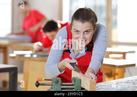 Zielgerichteter Trainee, der Sicherheitsschutz mit einer Säge trägt Stockfoto