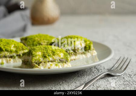 Traditionelles türkisches neues Dessert kalte Milchbaklava mit Pistazien auf weißem rustikalem Tisch, ramadan- oder Urlaubsdesserts-Konzept Stockfoto