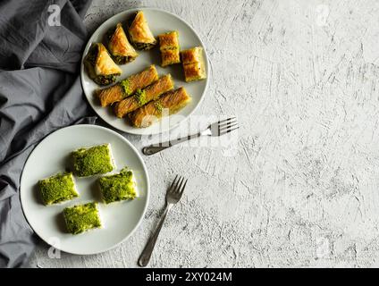 Traditionelle türkische verschiedene Pistazienbaklava, burma Kadayif und milchig kalte Baklava auf Teller auf weißem rustikalem Tisch, Urlaubs-Dessert-Konzept Stockfoto