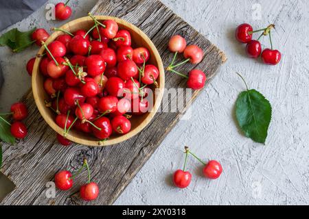Frische reife rote Kirschen in der Schüssel auf weißem Steinhintergrund, Haufen von Sommerfrüchten Konzept Stockfoto