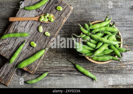 Frische, breite Bohnen mit Schote auf rustikalem Hintergrund, gesundes Essen Stockfoto