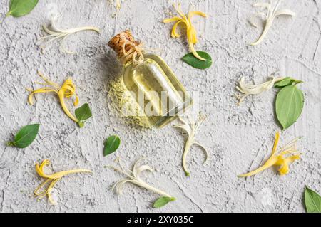 Glasflasche mit ätherischem Geißblatt-Öl mit frischen Blumen, lonicera caprifolium Stockfoto