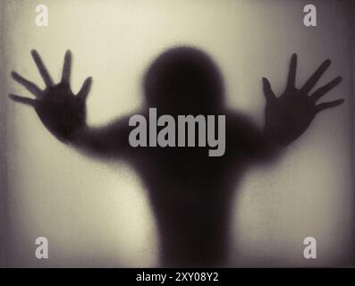Silhouette durch mattiertes Glas. Der Geist hinter dem Milchglas, Halloween-Feiertag. Stockfoto