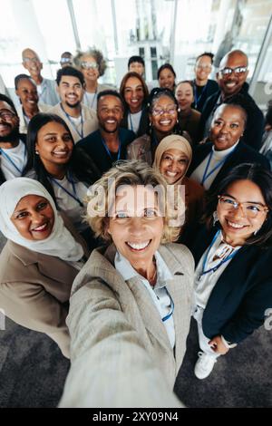 Eine vielfältige Gruppe von Firmenmitarbeitern lächelt und macht ein Selfie im Büro. Teamwork, Einheit und positive Unternehmenskultur in einem einzigen Schritt. Stockfoto