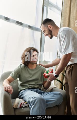 Ein Mann schenkt seinem Partner ein Geschenk in seinem Wohnzimmer. Stockfoto