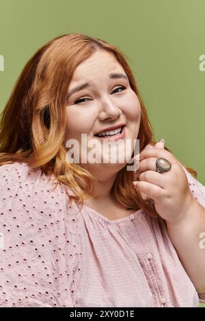 Eine Frau mit hellbraunem Haar lächelt strahlend, in einer zarten rosa Bluse. Stockfoto