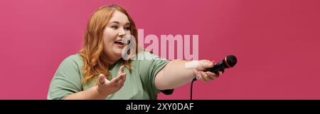 Eine Frau singt in ein Mikrofon, lächelt und mit der anderen Hand gespendet. Stockfoto