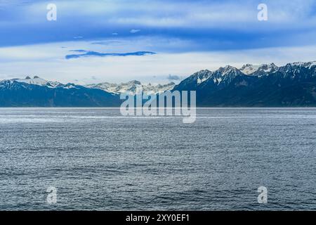 Vom Fährhafen Lausanne-Ouchy in östlicher Richtung am Genfersee. In der Ferne sind Montreux und Port Wallis. Mit schneebedeckten Bergen darüber. Stockfoto