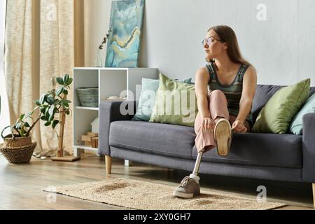 Eine junge Frau mit einer Beinprothese sitzt bequem auf einer Couch in ihrem Wohnzimmer und genießt die friedliche Atmosphäre. Stockfoto