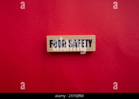 Lebensmittelsicherheitsnachricht auf Holzblock mit rotem Hintergrund. Begriffliches Symbol für Lebensmittelsicherheit. Kopierbereich. Stockfoto