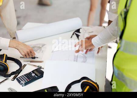 Zusammenarbeit der Architekten bei der Erstellung von Bauplänen an einem Arbeitsplatz mit Blueprint und Tools Stockfoto