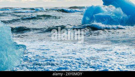 Das Meer ist ruhig und blau mit ein paar Eisbrocken, die an der Oberfläche schweben. Das Wasser ist ruhig und friedlich, mit kleinen Wellen. Die Eisstücke sind scatt Stockfoto