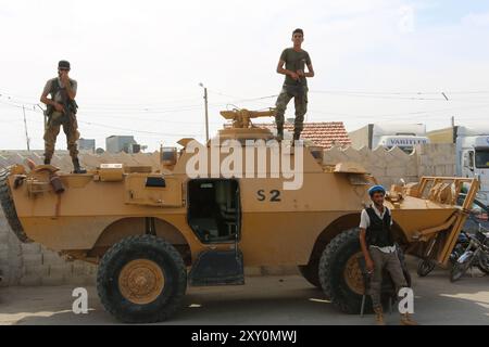 Azaz, Syrien. 11. Oktober 2019. Freie syrische Armeemitglieder bewachen Demonstranten von einem gepanzerten Fahrzeug am Grenzübergang Bab al-Salama im Nordosten Syriens, nahe der syrisch-türkischen Grenze. Syrer, die ursprünglich aus Dörfern stammen, die von den syrischen Demokratischen Kräften (SDF) und der kurdischen PKK-Partei kontrolliert wurden, demonstrierten im Nordosten von Azaz, um die türkische Militäroffensive „Friedensfrühling“ in Nordsyrien zu unterstützen. Sowohl Erwachsene als auch Kinder bekundeten ihre Unterstützung für die kürzlich begonnene Militäroperation der Türkei und der von der Türkei unterstützten Freien Syrischen Armee, die offiziell als syrische Nationalarmee bekannt ist Stockfoto