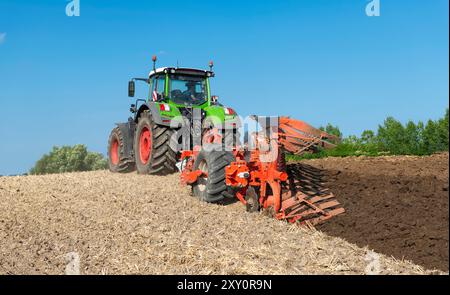 Traktor mit 7-Blatt-Umkehrpflug und Packer auf dem Feld, nach der Getreideernte - 2184 Stockfoto