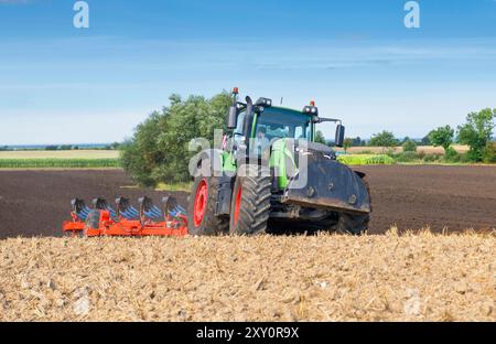 Traktor mit 7-Blatt-Umkehrpflug und Packer auf dem Feld, nach der Getreideernte - 2144 Stockfoto
