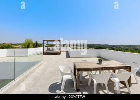 Eine geräumige und moderne Dachterrasse mit stilvoller Pergola, Esstisch und Panoramablick auf eine üppige Landschaft, perfekt für Entspannung im Freien Stockfoto