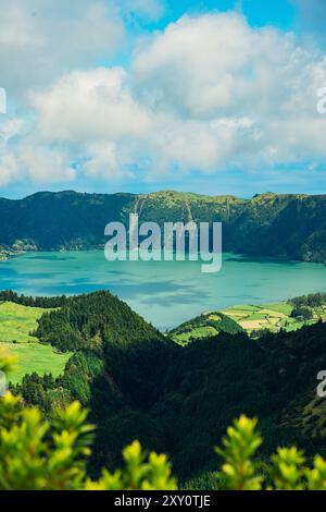 Ein atemberaubender Blick auf üppige grüne Hügel und einen ruhigen See eingebettet in die vulkanische Landschaft der Azoren, die reichen Farben der Natur und der lebendige Himmel po Stockfoto